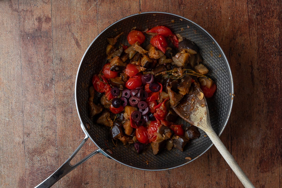 aubergine cooking in pan with tomatoes and olives
